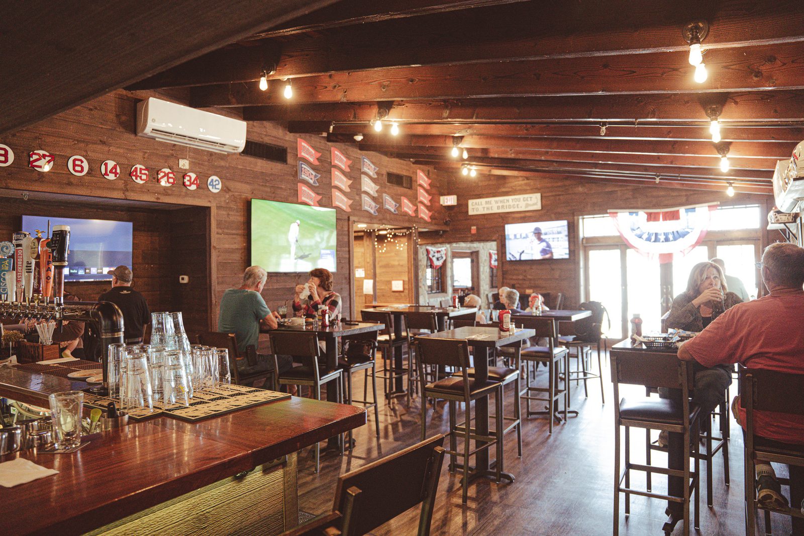 The taproom, with tables, TVs, and people at the bar